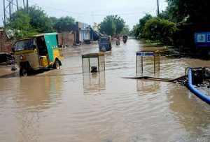 A rickshaw driver struggles to make his way through a flooded road submerged by stagnant rainwater near Old Civil Lines.