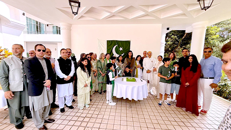 High Commissioner Rabia Shafiq, joined by members of the Pakistani community, cuts a cake to mark the 79th Independence Day of Pakistan during a flag-hoisting ceremony at Pakistan House