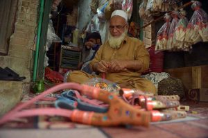 A vendor checks wooden slingshots at his workplace in the Dabgari area