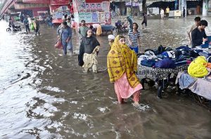 Auto rickshaws passing through rain water accumulated on road after heavy rain in the city