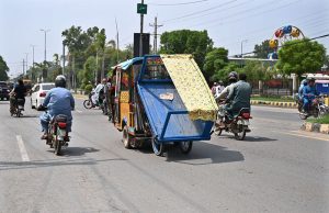 A rickshaw driver transports a handcart along a busy road in the city, posing a potential safety risk to motorists and other road users.