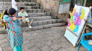 A young girl takes careful aim at a colourful array of balloons during a shooting game at Shakarpatrian area in the Federal Capital