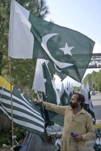 A customer selects a Kashmir flag from a seasonal vendor displaying national flags at a roadside stall on Zero Point ahead of Pakistan’s 79th Independence Day celebrations on August 14.