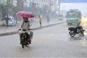 Auto rickshaws passing through rain water accumulated on road after heavy rain in the city