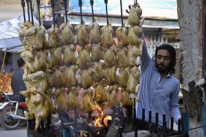 A street food specialist prepares traditional, mouth-watering 'Chicken Sajji' at his stall in Bani Market; the appetizing aroma of this popular dish is drawing customers in across the twin cities.