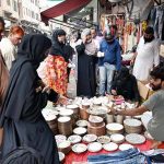 Families buy utensils from a roadside vendor during routine business activity in the city