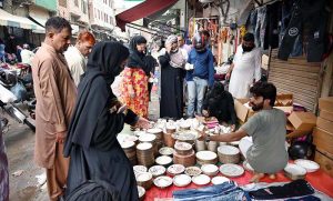 Families buy utensils from a roadside vendor during routine business activity in the city