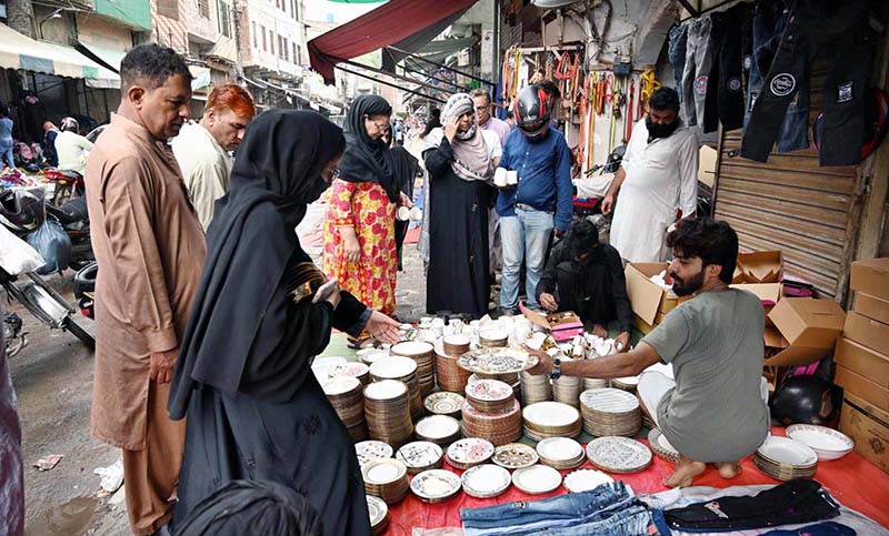 Families buy utensils from a roadside vendor during routine business activity in the city