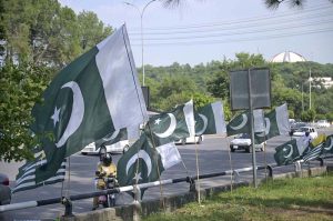 A customer selects a Kashmir flag from a seasonal vendor displaying national flags at a roadside stall on Zero Point ahead of Pakistan’s 79th Independence Day celebrations on August 14.