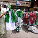 A vendor displays national flag-themed children’s outfits to attract customers as the nation prepares to celebrate Pakistan’s 79th Independence Day on August 14
