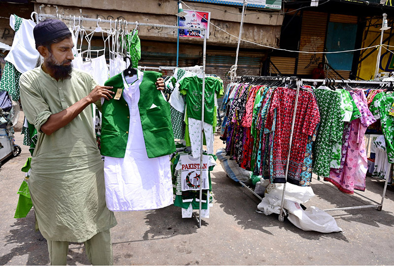 A vendor displays national flag-themed children’s outfits to attract customers as the nation prepares to celebrate Pakistan’s 79th Independence Day on August 14