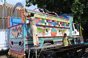 Labourers unload bundles of sugarcane from a delivery truck at the Fruit Market in the Federal Capital