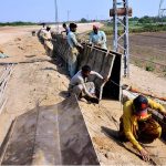 Labourers work on the construction of an embankment wall along the Indus River at Latifabad Unit No. 4 as part of a development project aimed at protecting local communities
