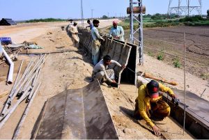 Labourers work on the construction of an embankment wall along the Indus River at Latifabad Unit No. 4 as part of a development project aimed at protecting local communities