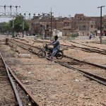 A motorcyclist crosses the railway track near the railway station, risking a possible accident