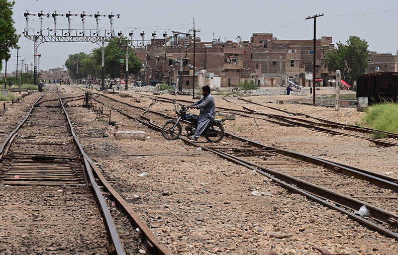 A motorcyclist crosses the railway track near the railway station, risking a possible accident