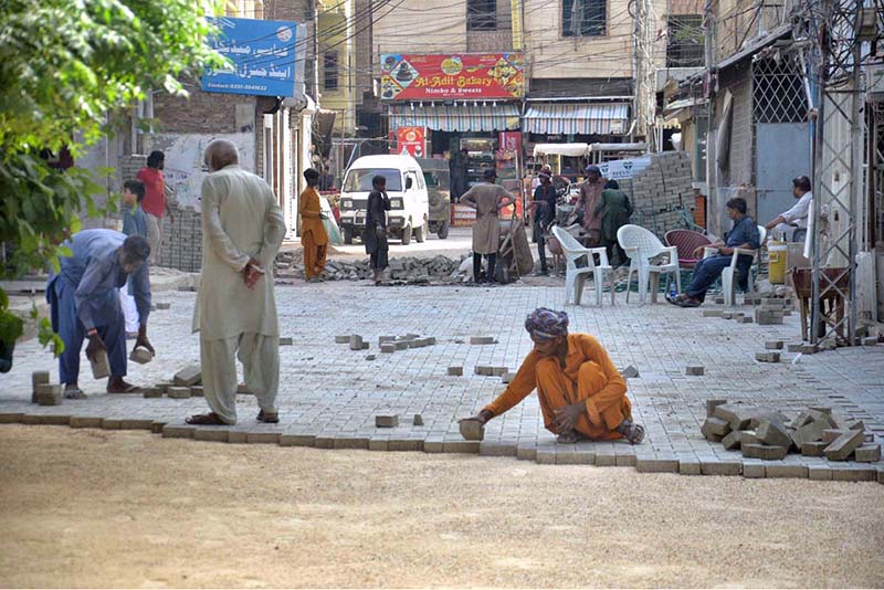 Labourers are busy fixing cemented tiles on road at GOR Colony
