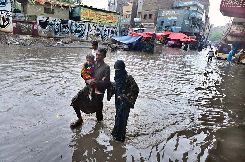A family makes its way through rainwater accumulated on a road during heavy rainfall in the city