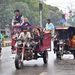 A nomadic family travels on an auto-rickshaw along Mall Road during routine traffic movement in the city