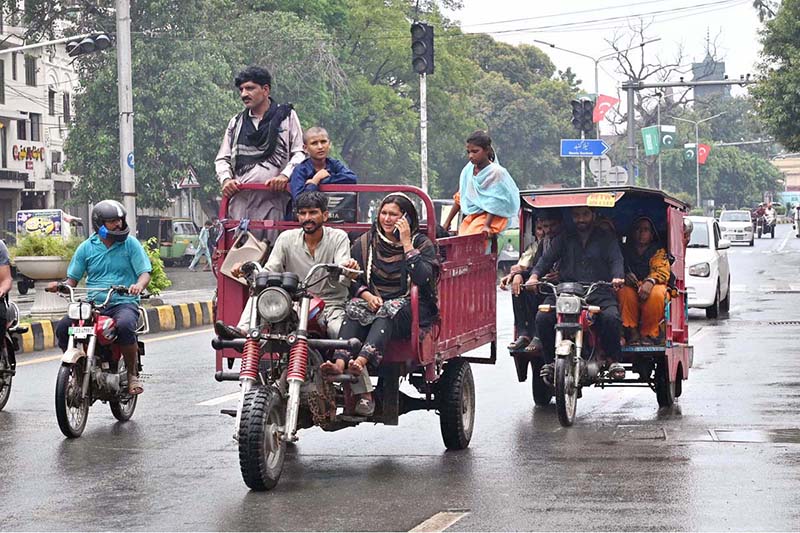 A nomadic family travels on an auto-rickshaw along Mall Road during routine traffic movement in the city