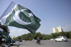 A customer selects a Kashmir flag from a seasonal vendor displaying national flags at a roadside stall on Zero Point ahead of Pakistan’s 79th Independence Day celebrations on August 14.