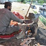 A vendor roasts corn cobs at his roadside setup near the Pirwadhai area in the Federal Capital