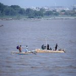 Fishermen stand on boats while fishing in the Indus River
