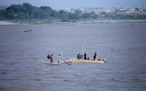Fishermen stand on boats while fishing in the Indus River