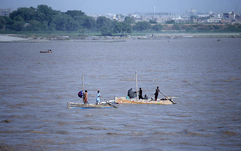 Fishermen stand on boats while fishing in the Indus River