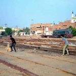 A group of youngsters playing cricket along railway tracks near railway station