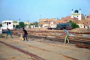 A group of youngsters playing cricket along railway tracks near railway station