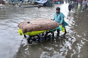 A family makes its way through rainwater accumulated on a road during heavy rainfall in the city