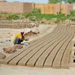 A worker molds raw clay into bricks at a brick-making site on the outskirts of the city
