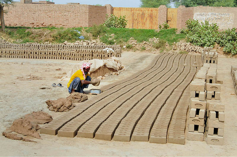 A worker molds raw clay into bricks at a brick-making site on the outskirts of the city