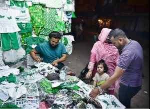 A vendor displays national flag-themed children’s outfits to attract customers as the nation prepares to celebrate Pakistan’s 79th Independence Day on August 14