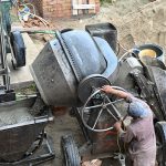 A labourer operates a cement mixer machine at a construction site in the Federal Capital