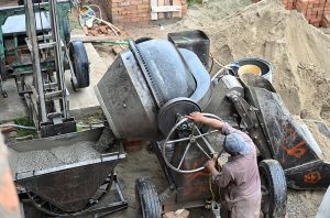 A labourer operates a cement mixer machine at a construction site in the Federal Capital