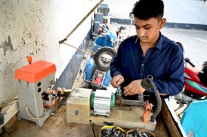 A young worker operates a key-cutting machine at a workshop