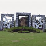 A gardener mows the lawn along the green belt on Faisal Avenue, featuring a portrait of Quaid-e-Azam Muhammad Ali Jinnah in the Federal Capital