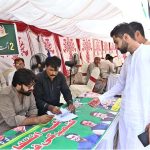 A voter receives assistance at the polling slip counter before casting his vote during the Azad Jammu and Kashmir Legislative Assembly elections at polling station LA-34