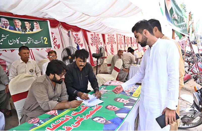 A voter receives assistance at the polling slip counter before casting his vote during the Azad Jammu and Kashmir Legislative Assembly elections at polling station LA-34