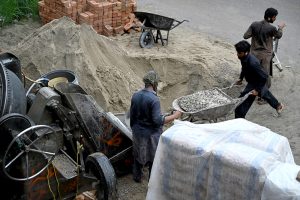 A labourer operates a cement mixer machine at a construction site in the Federal Capital