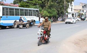 A policeman rides a motorcycle without wearing helmets near the District Police Officer (DPO) Office in the city, in apparent violation of traffic safety regulations.