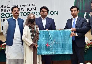 Commissioner Sargodha Hafiz Shaukat Ali and Chairman Board of Intermediate and Secondary Education (BISE) Sargodha Abbas Haider Gondal present an award to the first position holder in the Matriculation Examination 2026 during a prize distribution ceremony at the BISE Multipurpose Hall.