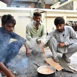 Workers at a construction site prepare tea on a makeshift wood-fired stove during their morning break