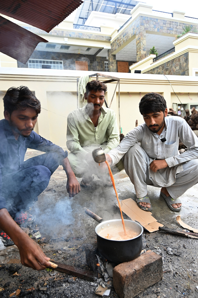 Workers at a construction site prepare tea on a makeshift wood-fired stove during their morning break