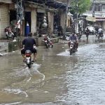 Motorcyclists navigate a flooded road following a torrential monsoon rain spell at Imam bara chowk in the twin cities