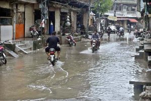 Motorcyclists navigate a flooded road following a torrential monsoon rain spell at Imam bara chowk in the twin cities