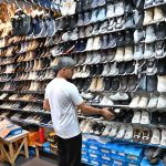 Customers select and purchase affordable imported and second-hand footwear at a shop in the weekly Sunday Bazaar near Peshawar Morr in the Federal Capital