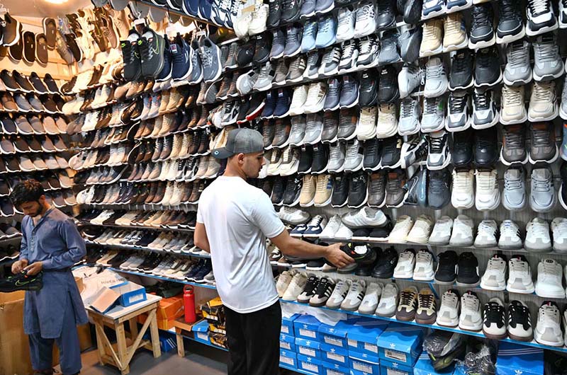 Customers select and purchase affordable imported and second-hand footwear at a shop in the weekly Sunday Bazaar near Peshawar Morr in the Federal Capital